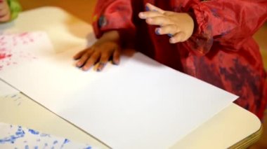 Okulda küçük bir kız elleriyle resim yapıyor. Kağıdı kapat