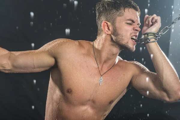 Homem forte em correntes posando sob a chuva, aqua studio — Fotografia de Stock