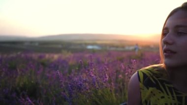 Güzel genç kadın çiftçi gün batımında lavanta tarlasında lavanta çiçeklerini kokluyor.
