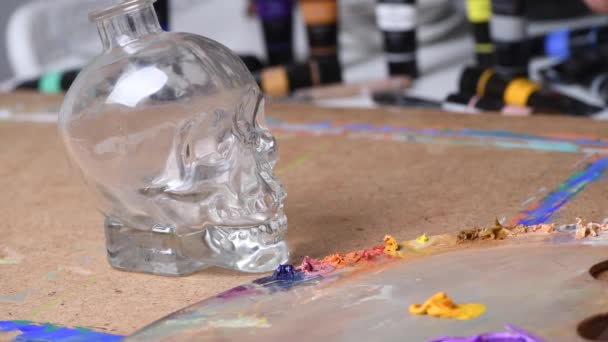 Croquis d'un dessin au pinceau jaune sur une bouteille en verre en forme de crâne — Video