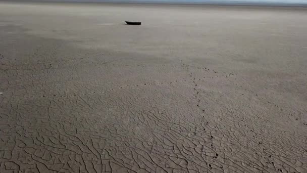 Vista superior del barco en la orilla del mar seco, el calentamiento global y el concepto de sequía. Clima ventoso paisaje desértico con huellas humanas y animales en arcilla seca. Imágenes sin clasificar de drones cinematográficos de alta calidad de 4k — Vídeos de Stock