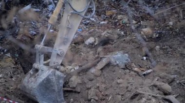 Escavator, kar yağarken donmuş zemini kazıyor. Köyde yaşayan eski bir evin yeniden inşası. Kentsel Yenilenme 4k yüksek kaliteli sinematik video