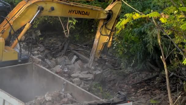 Rostov-on-Don, Rússia - 21 de novembro de 2021: A escavadora Hyundai quebra uma antiga casa vintage. construção de novos edifícios no local de habitação abandonada. Renovação urbana 4k Vídeo de alta qualidade — Vídeo de Stock
