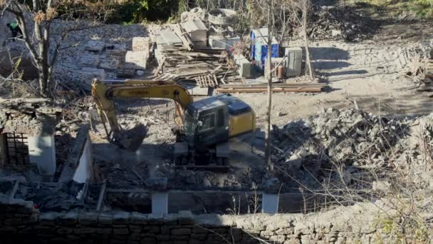 Rostov-on-Don, Rússia - 21 de novembro de 2021: A escavadora Volvo quebra uma antiga casa vintage. construção de novos edifícios no local de habitação abandonada. Renovação urbana 4k Vídeo de alta qualidade — Vídeo de Stock