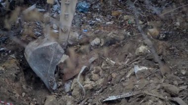 Escavator, kar yağarken donmuş zemini kazıyor. Kışın kır köyünde yaşayan eski bir evin yeniden inşası. Kentsel Yenilenme 4k yüksek kaliteli sinematik video
