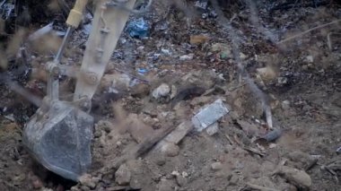 Escavator, kar yağarken donmuş zemini kazıyor. Kışın kır köyünde yaşayan eski bir evin yeniden inşası. Kentsel Yenilenme 4k yüksek kaliteli sinematik video