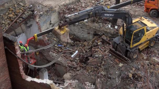Rosztov-on-Don, Oroszország - 2021. november 21: A Volvo exkavátor lerombol egy régi vintage házat. új épületek építése az elhagyatott lakások területén. Városi megújulás 4k Kiváló minőségű videó — Stock videók