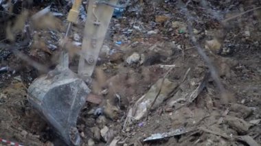 Escavator, kar yağarken donmuş zemini kazıyor. Kışın kır köyünde yaşayan eski bir evin yeniden inşası. Kentsel Yenilenme 4k yüksek kaliteli sinematik video