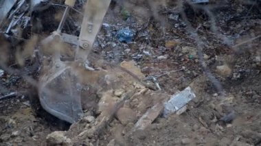 Escavator, kar yağarken donmuş zemini kazıyor. Kışın kır köyünde yaşayan eski bir evin yeniden inşası. Kentsel Yenilenme 4k yüksek kaliteli sinematik video