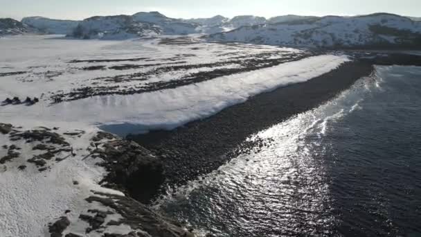 Vuelo aéreo de invierno sobre las olas rodando en la orilla ártica del océano con piedras redondas, olas oceánicas en la tormenta, video de drones de alta calidad 4k en invierno — Vídeos de Stock