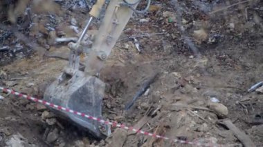 Escavator, kar yağarken donmuş zemini kazıyor. Kışın kır köyünde yaşayan eski bir evin yeniden inşası. Kentsel Yenilenme 4k yüksek kaliteli sinematik video