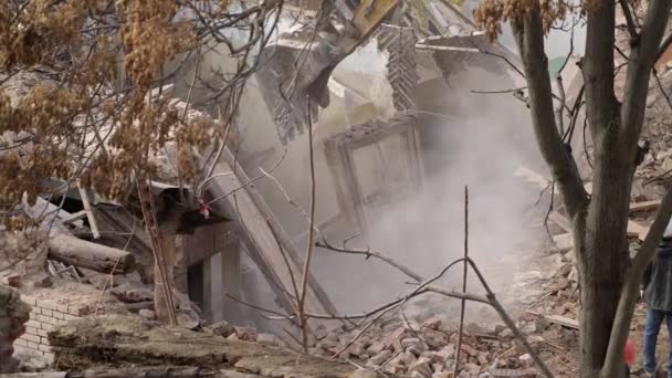 A védősisakos mérnök megnézi a bontást, a régi épület lerombolását, a kotró lerombolja a régi házat. Élő tárgy dekonstrukciója. Városi megújulás 4k Kiváló minőségű lassított felvétel — Stock videók