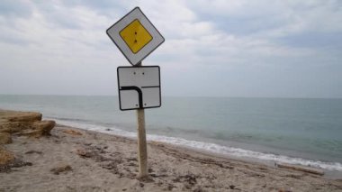 Kaynayan denizin kıyısındaki ana yolun yönünü gösteren iki yol işareti.