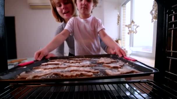 Giovane mamma con i capelli corti rossi e il figlio biondo mettere biscotti di pan di zenzero fatti in casa in forno — Video Stock