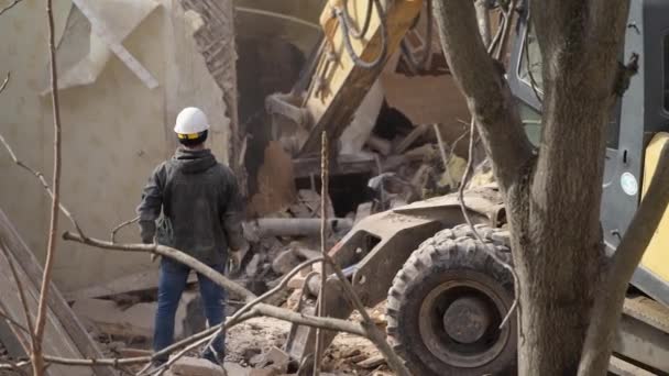 Ingenieur met beschermende helm kijkt naar sloop, vernietiging van oud gebouw, graafmachine breekt vintage huis. Deconstructie van levend object. Urban Renewal 4k Hoge kwaliteit slow motion video — Stockvideo