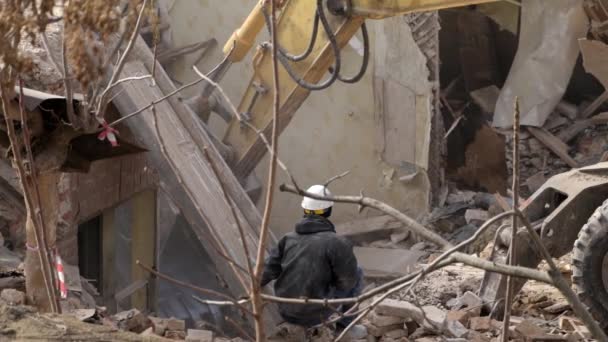 Inginer cu cască de protecție se uită la demolare, distrugerea clădirii vechi, excavatorul descompune casa de epocă. Deconstrucția obiectului viu. Reînnoire urbană 4k De înaltă calitate lent motion video — Videoclip de stoc