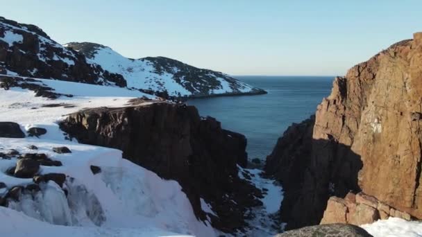 Vuelo aéreo de invierno a través de la cima del cañón escénico sobre las olas rodando en la orilla ártica del océano con piedras redondas, olas oceánicas en la tormenta, video de drones de alta calidad 4k en invierno — Vídeos de Stock