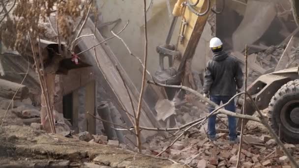 Engineer with protective helmet looks at demolition, destruction of old building, excavator breaks down vintage house. Deconstruction of living object. Urban Renewal 4k High quality slow motion video — Stock Video