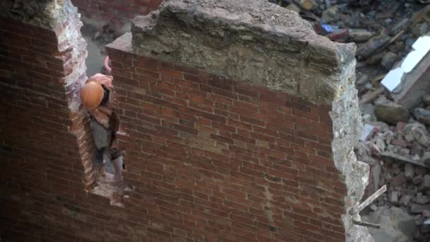 拆掉那栋废弃的老房子，戴着橙色头盔的工人用手提钻推倒了墙壁。住宅的解构。市区重建4k优质影片 — 图库视频影像