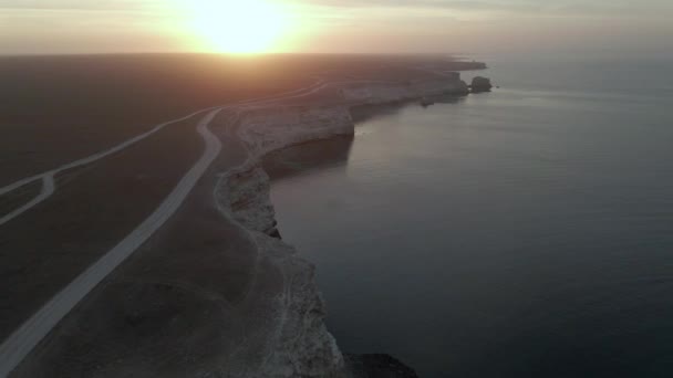 Два моря, разделенных побережьем на фоне желто-розового солнца вид сверху — стоковое видео