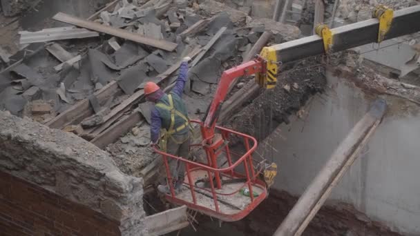 拆除废弃的老房子，工人戴着橙色头盔在吊篮摧毁木制屋顶用链锯。住宅的解构。市区重建4k优质影片 — 图库视频影像