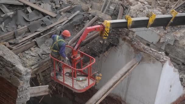 Demolición de la antigua casa abandonada, obrero en casco naranja en la cesta de la grúa destruir el techo de madera con motosierra. Deconstrucción de la casa viviente. Renovación urbana 4k Video de alta calidad — Vídeos de Stock