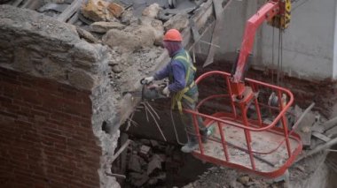 Eski terk edilmiş evin yıkılması, turuncu kasklı işçinin vinç sepetinde çalışması elektrikli testereyle ahşap çatıyı tahrip etmesi. Oturma odasının yeniden inşası. Kentsel Yenilenme 4k Yüksek kalite video