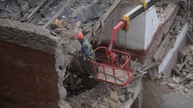 Eski terk edilmiş evin yıkılması, turuncu kasklı işçinin vinç sepetinde çalışması elektrikli testereyle ahşap çatıyı tahrip etmesi. Oturma odasının yeniden inşası. Kentsel Yenilenme 4k Yüksek kalite video