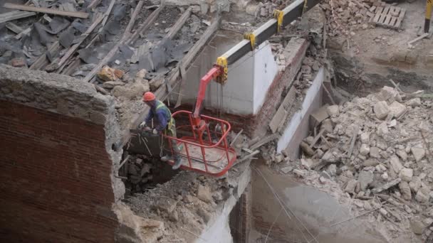 Demolición de la antigua casa abandonada, obrero en casco naranja en la cesta de la grúa destruir el techo de madera con motosierra. Deconstrucción de la casa viviente. Renovación urbana 4k Video de alta calidad — Vídeos de Stock