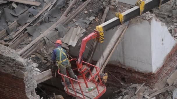 Demolizione di vecchia casa abbandonata, operaio in casco arancione a cesto gru distruggere tetto in legno con motosega. La decostruzione del soggiorno. Rinnovamento urbano 4k Video di alta qualità — Video Stock