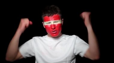 Happy taraftarı takımının zaferini kutluyor. Yüzü ulusal renklerle boyanmış genç bir adam. Mutlu bir adamın portresi milli takımını destekliyor.