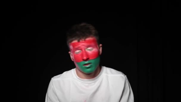 Happy fan celebrate victory of his team. Young man with face painted in national colours. Portrait of a happy man supports his national team at home — Stock Video