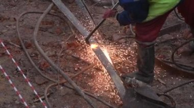 Metal kaynakçı binanın dışında çalışıyor. İnsan metalin parçalarını demirden kaynaklıyor. Parlak kıvılcımlar yavaş çekimde. 4k Yüksek kalite sinematik yavaş çekim, 120 fps