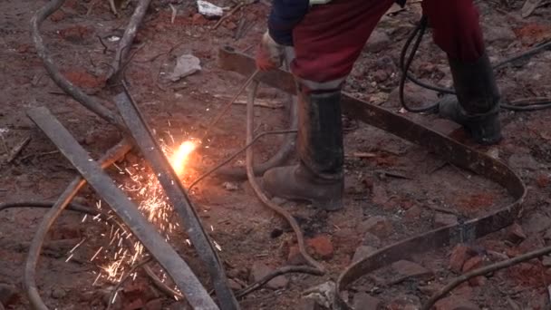 Spawacz metali pracuje na zewnątrz budynku. Człowiek spawa części konstrukcji metalowej z żelaza. Jasne iskry w zwolnionym tempie. 4k Wysokiej jakości filmik spowolniony, 120 fps — Wideo stockowe