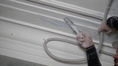 Koruyucu miğferli şişman sakallı yetişkin adam inşaat beyazlatıcısının yüksek tavanını kaldırıyor. Tamiratı kendi el konseptinle yap. 4k yavaş çekim 120 fp 
