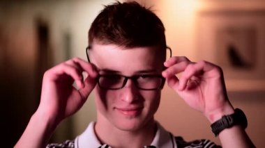 Genç yakışıklı adam kameraya poz veriyor. Yakışıklı duygusal adam. Genç adam farklı duygular yaşıyor. Kalkıyor ve şık gözlükler takıyor..