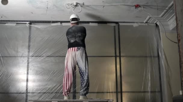 Portret szczęśliwego amerykańskiego budowlańca w mundurze tańczącego i uśmiechniętego wykonującego remont domu. Wesoły Amerykanin w kasku i goglach tańczący podczas remontu domu — Wideo stockowe