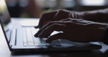 Serbest çalışanların ellerinin klavyeye yazı yazarken ve kafede akıllı telefon kullanırken yandan görüntüsü. Adam dizüstü bilgisayarda çalışıyor, sonra da cep telefonunu alıyor. Yakın çekim, yavaş çekim