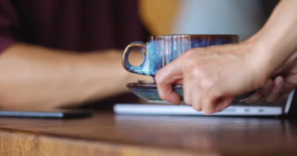 Bir kafede otururken elleri gri dizüstü bilgisayarda yazan bir adam. Garson bir fincan kahve getiriyor. — Stok video