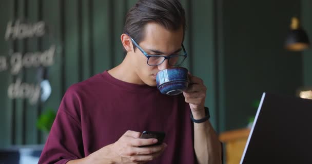 Mladý freelancer pomocí smartphonu a notebooku v kavárně.Freelance koncept — Stock video