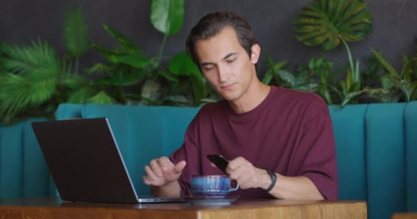 Muž pracující na notebooku v kavárně.Guy brát telefon a dostat naštvaný čtení špatné zprávy a smutné zprávy — Stock video