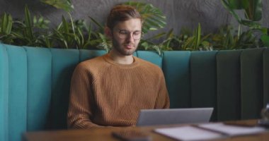  Uzaktan kumanda için dizüstü bilgisayarı kullanan bir adamın orta görüşü. Tabutta oturan gözlüklü, düşünceli, serbest çalışan bir iş adamı. Öğrenciler çevrimiçi çalışıyor