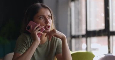 Ofiste çalışırken cep telefonuyla konuşan esmer saçlı çekici bir kadının portresi.