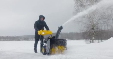 Adam avluda kar temizleme makinesiyle kar temizliyor. Yavaş çekim