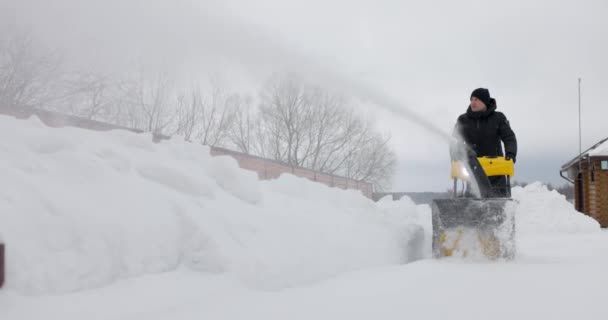 Seorang pria memindahkan salju dengan salju mekanis di halaman rumah. Bubuk salju. Gerakan lambat — Stok Video