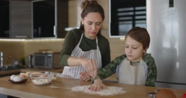 Mather mutfakta oğlunla iyi eğlenceler. Noel kurabiyeleri hazırlıyorlar ve unu masaya döküyorlar. Aile günü, yemek pişirme. Yavaş çekim