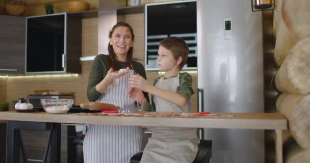 Mather haben Spaß mit Sohn in der Küche. Sie bereiten Weihnachtsplätzchen zu und gießen das Mehl auf den Tisch. Familientag, Kochen. Zeitlupe — Stockvideo