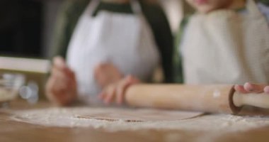 Anne ve küçük oğlu evde el yapımı kurabiyeler yapıyor, mutfakta çiğ hamuru birlikte yuvarlıyorlar. Küçük şef, aile birlikte vakit geçiriyor. Yakın çekim görüntüsü. Yavaş çekim