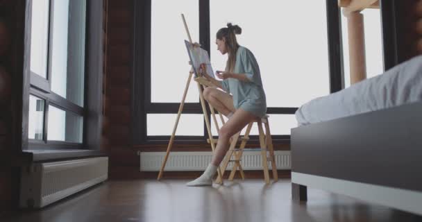 Art, creativity, hobby, job and creative occupation concept. Cute woman draws at home in bedroom near window in morning — Stock Video