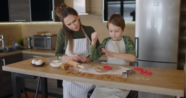 Genç bir aile annesi ve oğlu mutfakta ev yapımı kurabiyeler yapıyor. Sağlıklı yiyecekler, yaşam tarzı ve ebeveynlik kavramı. Yavaş çekim — Stok video